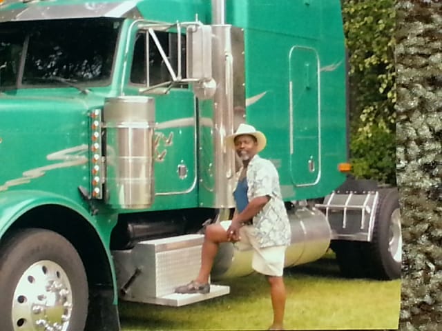 DeLond Parker, Sr. standing beside his green Peterbilt tractor